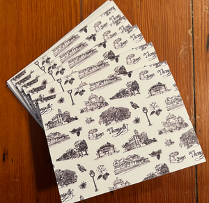There is a stack of black and white Toile of Thomasville notecards on top of a stack of white envelopes fanned out on a floor.