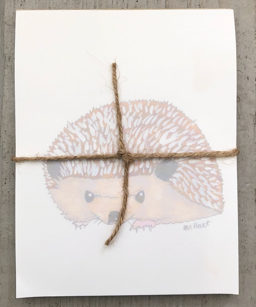 There is a notepad tied together with twice. The paper of the notepad is printed with a design of a hedgehog.