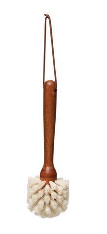 Pictured is a dish brush with a handle made from beech wood and a leather tie attached to it.