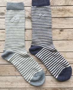 Pictured are two Samantha Holmes Alpaca Stripey Socks. There is one light blue sock and one dark blue sock. These are sold at The Hare & The Hart in Thomasville, GA.
