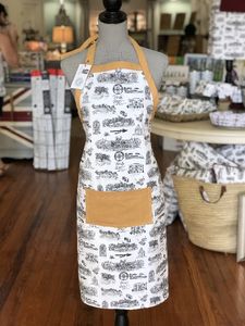 Pictured is a mannequin wearing a Toile of FSU apron. The fabric is black and white Toile of FSU patterned fabric. It has a pocket on the front and trim making up the top edge and the tie around the neck that are both made of gold fabric.